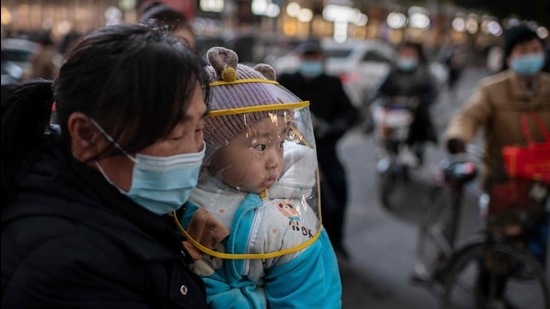 A woman wearing a face mask holds a baby that wears a protective shield during rush hour on a street outside of a shopping mall complex in the Chinese city of Wuhan on January 13. (AFP) A woman wearing a face mask holds a baby that wears a protective shield during rush hour on a street outside of a shopping mall complex in the Chinese city of Wuhan on January 13. (AFP)