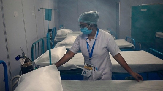 A medical staff arranges a bed after sanitization was done inside a makeshift isolation ward built to deal with suspected Covid-19 coronavirus patients as Hindu devotees gather at Sagar Island on January 12. India has logged 16,946 new infections in the preceding 24 hours, the ministry announced in its health update.(Dibyangshu Sarkar / AFP)
