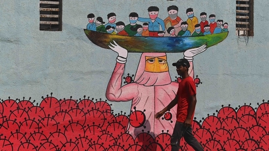A pedestrian walks past a wall mural depicting on Covid-19, on January 13 in Mumbai. With this latest rise, India’s tally of Covid-19 infections reached 10,512,093, the second-highest globally after that of the United States.(Indranil Mukherjee / AFP)