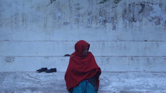 A woman sits as she covers herself with a shawl on a foggy morning on the bank of the river Yamuna, in New Delhi on Friday. (ANI Photo)