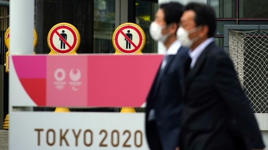 People wearing protective masks to help curb the spread of the coronavirus walk near a banner of Tokyo 2020 Olympics and Paralympic games in Tokyo Friday, Jan. 15, 2021. (AP) People wearing protective masks to help curb the spread of the coronavirus walk near a banner of Tokyo 2020 Olympics and Paralympic games in Tokyo Friday, Jan. 15, 2021. (AP)
