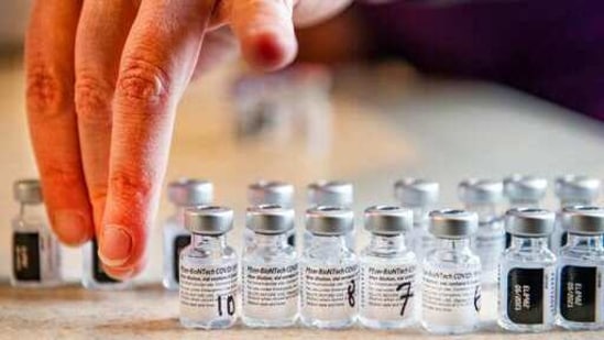 Pharmacist organizes the empty vials of the Pfizer-BioNTech Covid-19 vaccine.(AP) Pharmacist organizes the empty vials of the Pfizer-BioNTech Covid-19 vaccine.(AP)