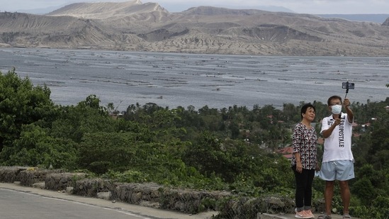 A couple poses for a selfie with the Taal volcano in background almost a year after it erupted, on January 10. The eruption delivered an early crisis in what would become a tough year in one of the world’s most disaster-prone nations. A couple of months after the volcano sent more than 376,000 people fleeing to safety, the Covid-19 pandemic hit the country.(Aaron Favila / AP)