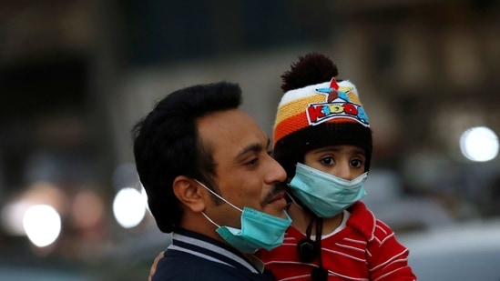 A man and child with protective masks walk outside a market as the coronavirus disease (Covid-19) pandemic continues, in Karachi, Pakistan. (Reuters)