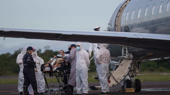 A Covid-19 patient, one of 12 to be transferred in a military airplane, is assisted by medical staff at the Ponta Pelada airport in Manaus, Amazonas State, Brazil, on January 15, 2021, amid the novel coronavirus pandemic.(AFP) A Covid-19 patient, one of 12 to be transferred in a military airplane, is assisted by medical staff at the Ponta Pelada airport in Manaus, Amazonas State, Brazil, on January 15, 2021, amid the novel coronavirus pandemic.(AFP)