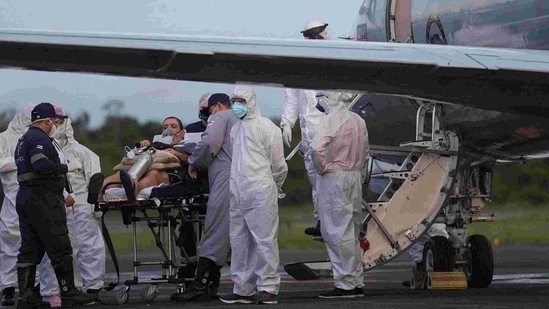 A Covid-19 patient, one of 12 to be transferred in a military airplane, is assisted by medical staff at the Ponta Pelada airport in Manaus, Amazonas State, Brazil, on January 15, 2021, amid the novel coronavirus pandemic.(AFP) A Covid-19 patient, one of 12 to be transferred in a military airplane, is assisted by medical staff at the Ponta Pelada airport in Manaus, Amazonas State, Brazil, on January 15, 2021, amid the novel coronavirus pandemic.(AFP)