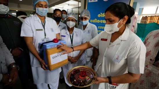 A nurse (R), performs rituals to a box containing Covid-19 vaccines upon its arrival at a government Hospital in Ahmedabad on January 16. Marking its feat in the history of disease outbreaks, India on January 16 started the world's largest Covid-19 vaccination drive where it will see the administration of the drug in 300,000 million healthcare workers.(Ajit Solanki / AP Photo)