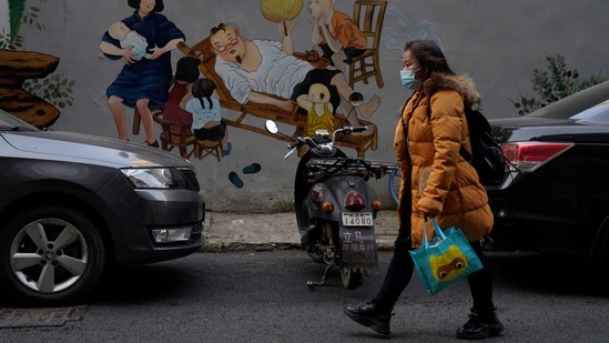 A resident wearing a mask past by a mural depicting idyllic home life in Wuhan in central China's Hubei province. (AP) A resident wearing a mask past by a mural depicting idyllic home life in Wuhan in central China's Hubei province. (AP)