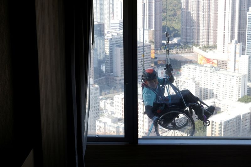 Lai Chi-wai, a paraplegic climber, attempts to climb the 320-metre tall Nina Tower. (REUTERS)