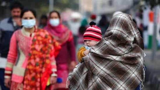 An Indian woman carrying a child crosses a road on a cold day in Jammu, India Sunday, January 17, 2021(AP) An Indian woman carrying a child crosses a road on a cold day in Jammu, India Sunday, January 17, 2021(AP)