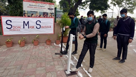 Students sanitize their hands before entering Kautilya Govt. Sarvodaya Bal Vidyalaya in Greater Kailash on January 18. Schools are also working out plans to ensure that students who choose not to come to campus, do not miss out anything.(Sanjeev Verma / HT Photo)
