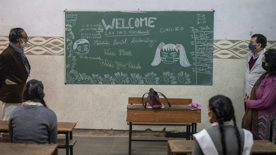 Officials from Delhi's education department look at a welcome message drawn on a board during an inspection of schools in New Delhi on January 18. Schools have also created posters to raise awareness on Covid-19 and also comfort students returning to school after a long break.(Altaf Qadri / AP)
