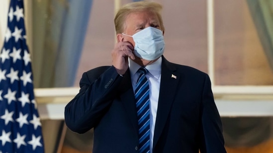 FILE - In this Oct. 5, 2020, file photo, President Donald Trump removes his mask as he stands on the Blue Room Balcony upon returning to the White House in Washington, after leaving Walter Reed National Military Medical Center, in Bethesda, Md. Trump announced he tested positive for COVID-19 on Oct. 2. (AP Photo/Alex Brandon, File)(AP)