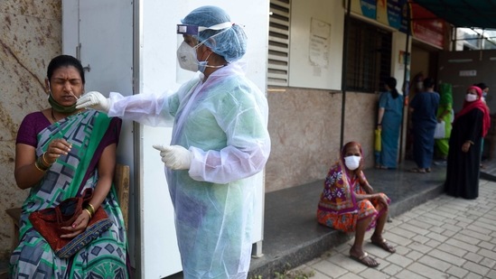 A BMC health care worker takes a swab from a woman to test for coronavirus infection, at Govandi in Mumbai on January 20. The number of active cases, which have already reached a record low, dropped further to 1,92,308, while 10,265,706 patients have been cured or discharged from hospitals.(Satish Bate / HT Photo)