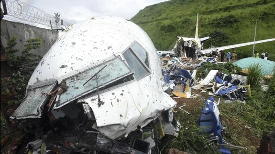 People stand by the debris of the Air India Express flight that skidded off a runway while landing in Kozhikode, Kerala, in August 2020. The special evacuation flight bringing people home to India who had been trapped abroad because of the coronavirus skidded off the runway and split in two while landing in heavy rain killing more than a dozen people and injuring dozens more. (AP) People stand by the debris of the Air India Express flight that skidded off a runway while landing in Kozhikode, Kerala, in August 2020. The special evacuation flight bringing people home to India who had been trapped abroad because of the coronavirus skidded off the runway and split in two while landing in heavy rain killing more than a dozen people and injuring dozens more. (AP)