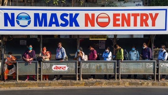 Commuters waiting at a bus stop early in the morning in Mumbai on January 21. Meanwhile, the world's largest Covid-19 vaccination programme has been going on in India, with a target of inoculating the healthcare and frontline workers. It was launched by Prime Minister Narendra Modi on January 16.(Punit Paranjpe / AFP)