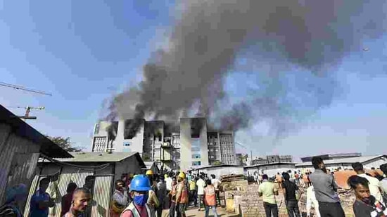 Workers rush out of the building after fire breaks out at Serum Institute of India, Pune, on Thursday. (PTI)