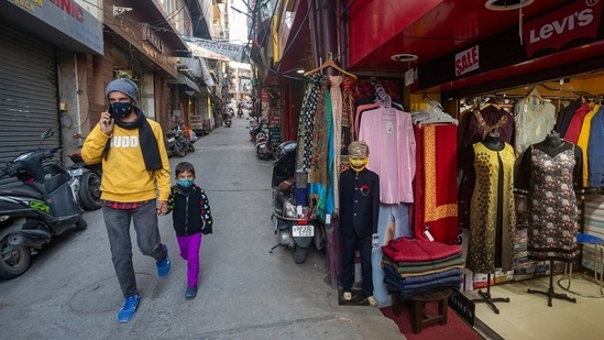 A man and a child wearing protective face masks walk past a garment store displaying a mannequin wearing a mask in Dharmshala on January 19. The country reported at least 600 adverse event following immunisation (AEFI) in the past five days, one of the lowest in the world, of which 82 were reported on January 20.( Ashwini Bhatia / AP)