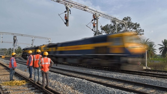 Workers on contract for Indian Railways, erect infrastructure for drawing electric cable lines over railway tracks for use by locomotives on the outskirts of Bangalore on January 15, 2021. (Photo by Manjunath Kiran / AFP)(AFP) Workers on contract for Indian Railways, erect infrastructure for drawing electric cable lines over railway tracks for use by locomotives on the outskirts of Bangalore on January 15, 2021. (Photo by Manjunath Kiran / AFP)(AFP)