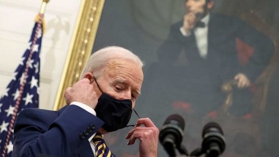 US President Joe Biden adjusts his face mask while speaking in the State Dining Room at the White House in Washington, US. (Reuters)