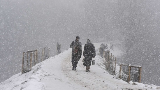People out during fresh snowfall in Srinagar on January 23. A yellow alert avalanche warning has been issued on January 24 by Disaster Management Authority of Jammu and Kashmir Government for several higher reaches of Jammu and Kashmir.(Waseem Andrabi / HT Photo)