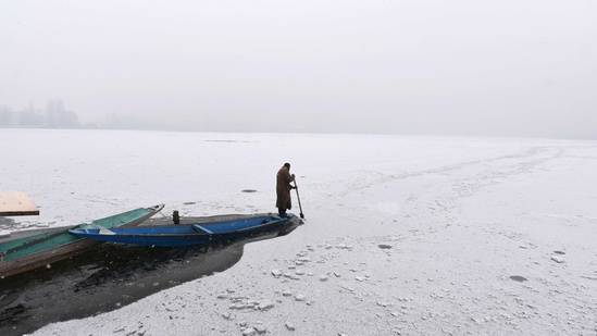A boatman breaks ice sheets while rowing along the frozen Dal Lake during snowfall in Srinagar on January 23. Jammu and Kashmir is witnessing a 40-day long period of harsh winter cold known as the 'Chillai Kalan', which will end on January 31.(Waseem Andrabi / HT Photo)