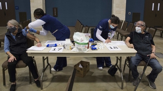 Rosilin Maxwell receives the Moderna coronavirus vaccine as her husband, Jimmy Maxwell, waits for her after also receiving the vaccine during mass vaccination at the New Braunfels Civic Convention Center in New Braunfels, Texas on January 21.(Mikala Compton / Herald-Zeitung via AP)