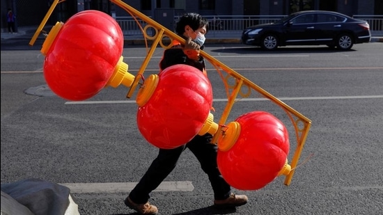 A person wearing a face mask carries street lights in the shape of Chinese lanterns ahead of the Chinese Lunar New Year holiday in Beijing, China on January 26, 2021. (REUTERS) A person wearing a face mask carries street lights in the shape of Chinese lanterns ahead of the Chinese Lunar New Year holiday in Beijing, China on January 26, 2021. (REUTERS)