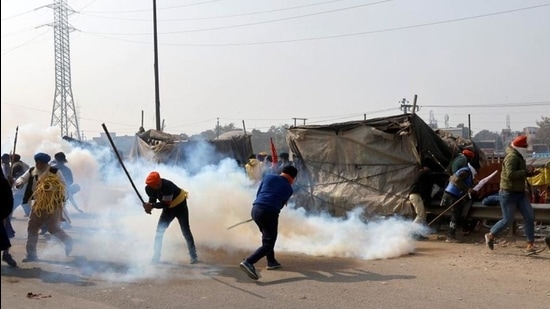 Farmers use sticks to push away tear smoke shells fired by police during a tractor rally to protest against farm laws on the occasion of India's Republic Day in Delhi. (REUTERS)