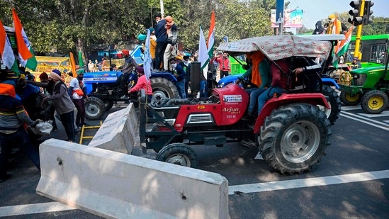 Farmers on tractors remove concrete barricades installed to prevent them from entering the city during the tractor rally in New Delhi on January 26.(Sajjad Hussain / AFP)