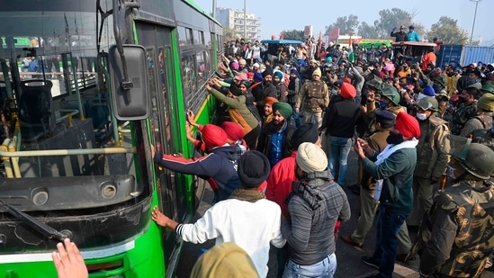 Farmers push aside a bus to pass along a road during the tractor rally, in New Delhi on Tuesday.(AFP Photo)