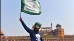 A farmer waves a flag as more farmers gather at Red Fort during their tractor parade on Republic Day, in New Delhi. (PTI) A farmer waves a flag as more farmers gather at Red Fort during their tractor parade on Republic Day, in New Delhi. (PTI)