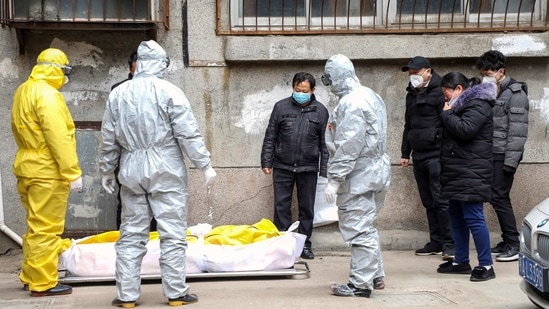In this file photo, funeral home workers remove the body of a person suspected to have died from the coronavirus from a residential building in Wuhan in central China's Hubei Province. A relative of a coronavirus victim in China is demanding to meet a visiting World Health Organization expert team, saying it should speak with affected families who allege they are being muffled by the Chinese government. (AP) In this file photo, funeral home workers remove the body of a person suspected to have died from the coronavirus from a residential building in Wuhan in central China's Hubei Province. A relative of a coronavirus victim in China is demanding to meet a visiting World Health Organization expert team, saying it should speak with affected families who allege they are being muffled by the Chinese government. (AP)
