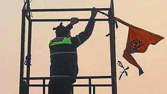 A security person at Red Fort takes off the Nishan Sahib flag that was hoisted there on Tuesday. (Sanchit Khanna/HT PHOTO)