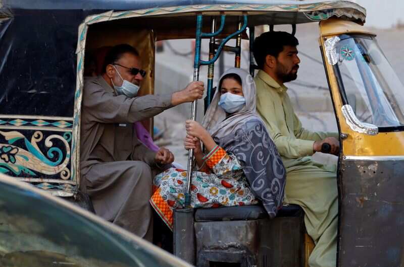 Pessoas com máscaras contra Covid-19 viajam de rikshaw (tok tok) em Karachi, Paquistão.  (Reuters)