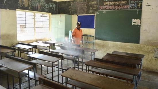 A municipal worker sanitises a classroom of a school. The state government has allowed classes 5 to 12 to resume but are yet to allow classes 1 to 4 to reopen. (PTI)