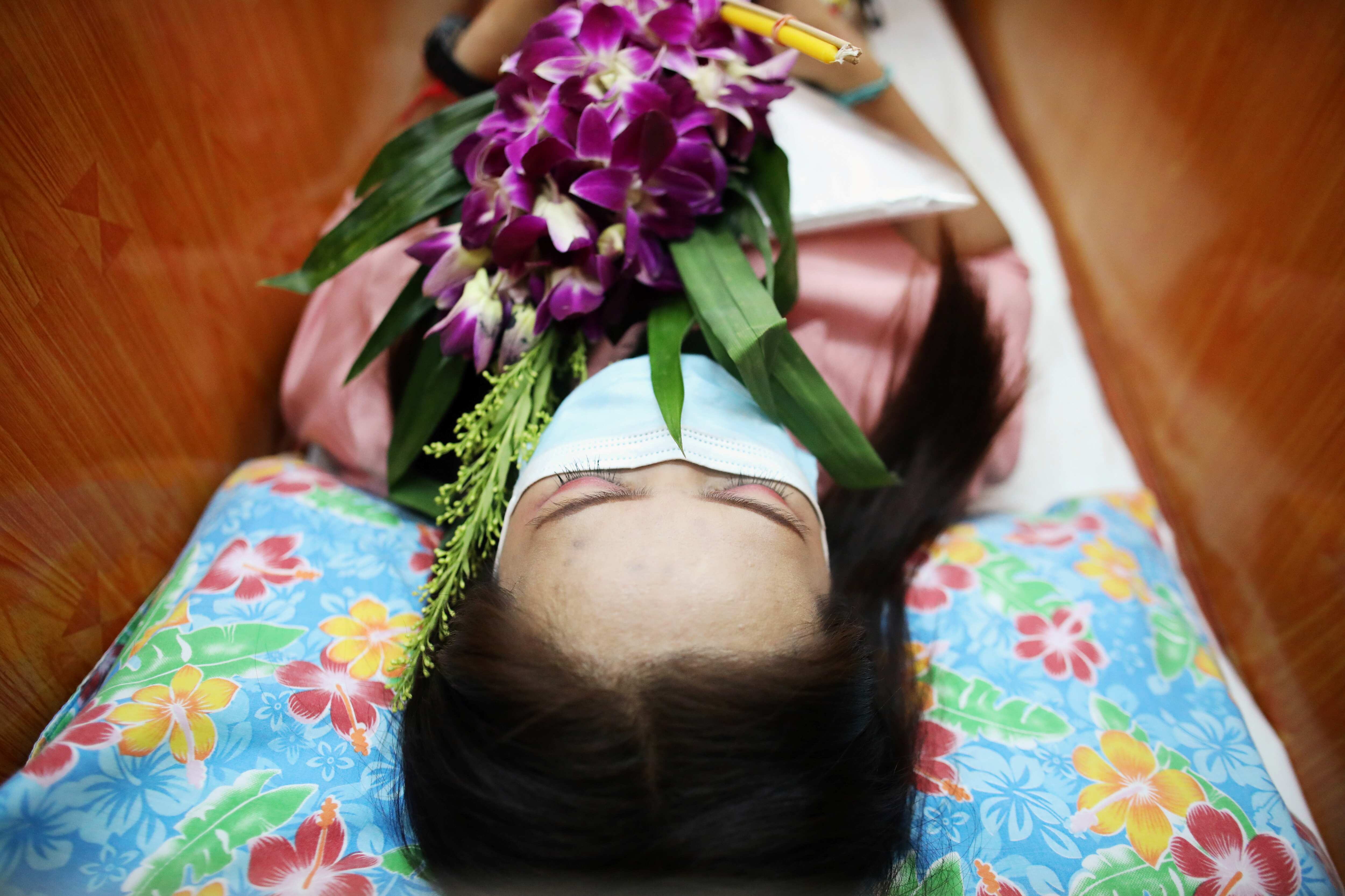 A devotee lies down and prays inside a coffin to trick death and improve luck at a temple in Bangkok, Thailand. (REUTERS)