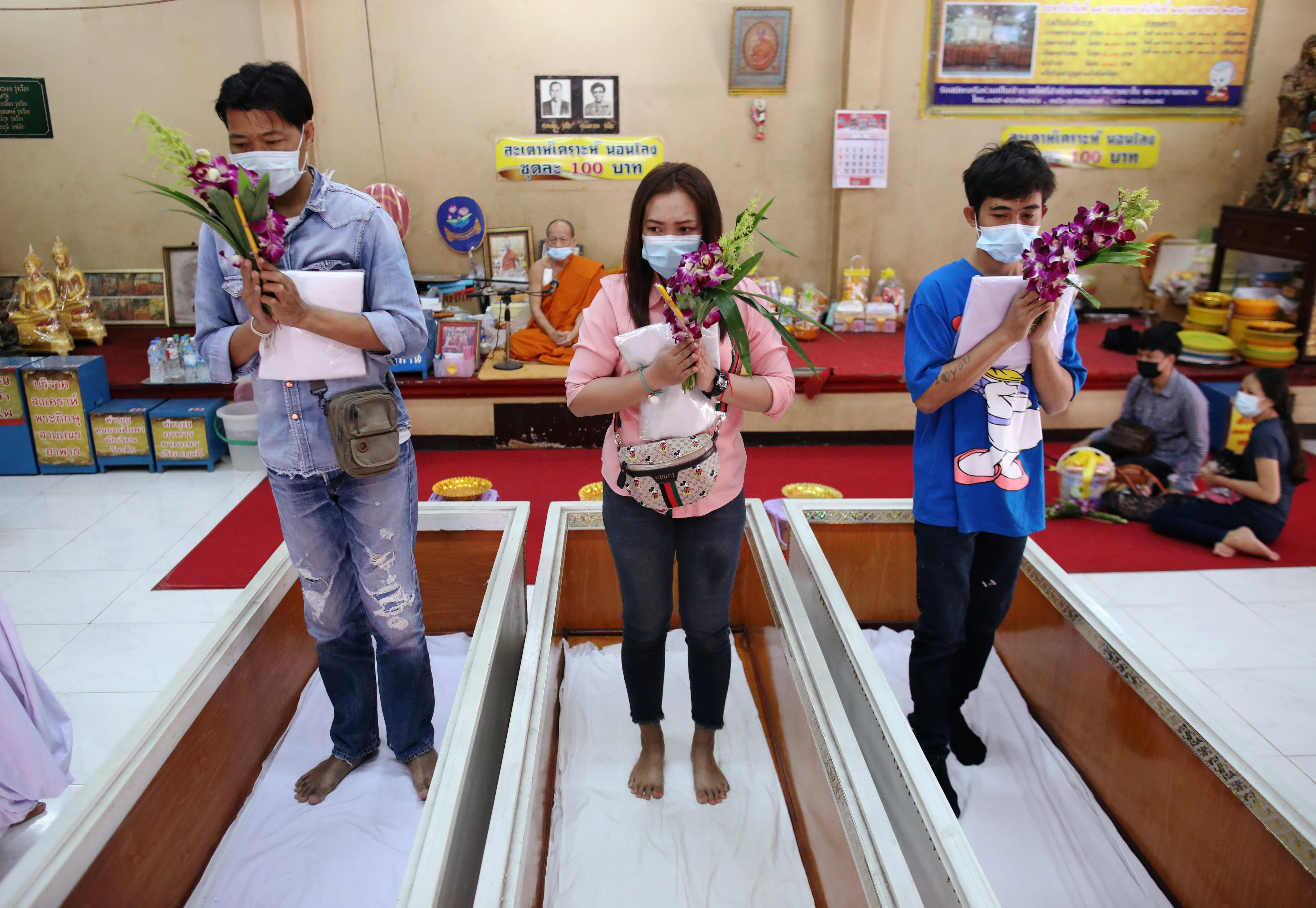 Devotees pray before lying down inside coffins to trick death and improve their luck at a temple in Bangkok, Thailand. (REUTERS)