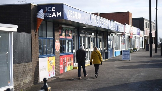 People walk along a high street of closed shops in Fleetwood, northwest England, on January 29, 2021 as life continues in Britain's third coronavirus lockdown. - UK citizens and permanent residents flying back from 22 countries deemed at "high risk" from Covid-19 variants must soon quarantine in hotels under new rules announced on January 27. The announcement came as the government signalled a current national lockdown would stay in force until at least March 8. (Photo by Oli SCARFF / AFP) (AFP) People walk along a high street of closed shops in Fleetwood, northwest England, on January 29, 2021 as life continues in Britain's third coronavirus lockdown. - UK citizens and permanent residents flying back from 22 countries deemed at "high risk" from Covid-19 variants must soon quarantine in hotels under new rules announced on January 27. The announcement came as the government signalled a current national lockdown would stay in force until at least March 8. (Photo by Oli SCARFF / AFP) (AFP)