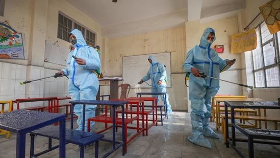 Jammu: Workers, wearing PPE, sanitise a classroom, ahead of reopening of educational institutions after a gap of over 10 months owing to the COVID-19 pandemic, in Jammu, Saturday, Jan. 30, 2021. (PTI Photo)(PTI01_30_2021_000069B)(PTI)