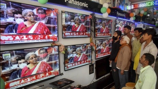 People watch finance minister Nirmala Sitharaman presenting Union Budget 2021-21 on television sets, at an electronics store in Prayagraj on Monday. (PTI)