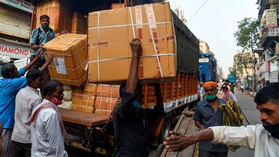 Workers unload boxes from a truck at a market during early morning in Mumbai on February 1. The government has proposed via the budget to incentivise incorporation of one person companies (OPCs), a move that will benefit startups and innovators and push the Atmanirbhar Bharat initiative.(Punit Paranjpe / AFP)