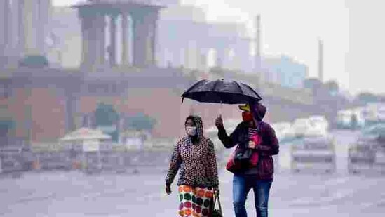 Commuters out in the rain at Vijay Chowk in New Delhi, India.(Arvind Yadav/HT PHOTO)