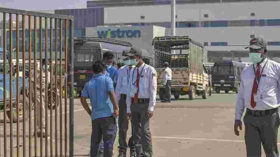 Security personnel stand guard outside Wistron Infocomm Manufacturing India Pvt Ltd, where a section of workers went on a rampage at its facility manufacturing Apple iPhones and other products over non-payment of promised wage, at Narasapura area in Bengaluru, Sunday, Dec. 13, 2020.(PTI)