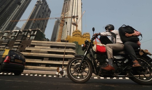 A man rides past buildings under construction in Mumbai. (AP Photo)
