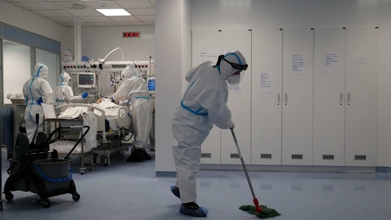 A cleaning worker mops the floor as medical staff examine a Covid-19 patient in an ICU of the Sotiria Thoracic Diseases Hospital in Athens. (AP) A cleaning worker mops the floor as medical staff examine a Covid-19 patient in an ICU of the Sotiria Thoracic Diseases Hospital in Athens. (AP)