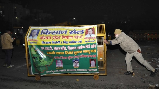 A police personnel moves a barrier in place, after the ongoing protest against the new farm laws was called off at Chilla (Delhi-UP border) near Noida on January 27. Protest sites in Chilla and Burari were vacated as some  farmer unions called off their agitation following the violence on January 26. (Sunil Ghosh / HT Photo)