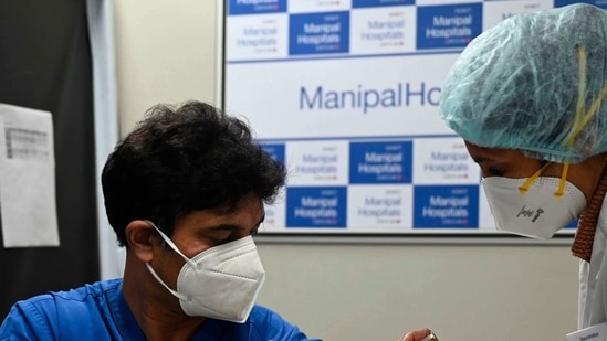 A medical worker (R) inoculates a medical staff with a Covid-19 coronavirus vaccine at the Manipal Hospital, in New Delhi.