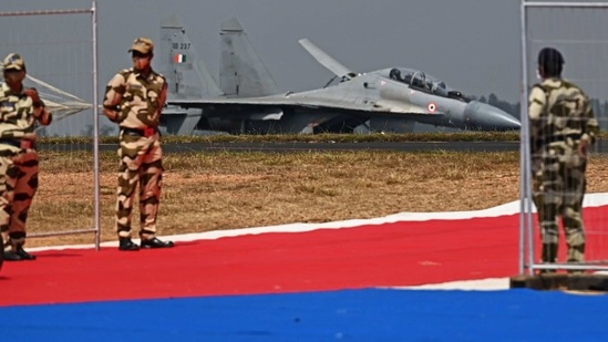 Security personnel stand guard as an Indian Air Force's Sukhoi Su-30MKI fighter jet lands during the first day of the Aero India 2021 air show in Bengaluru on Wednesday,(AFP Photo)