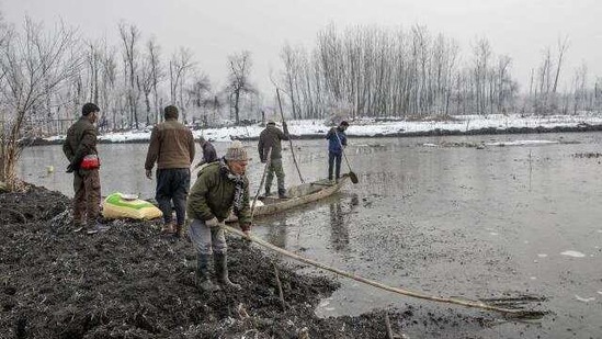 Ghulam Mohiuddin Dar, foreground, breaks ice with other wildlife officials in the frozen surface of a wetland in Hokersar, north of Srinagar, Indian controlled Kashmir, Friday, Jan. 22, 2021.(AP)